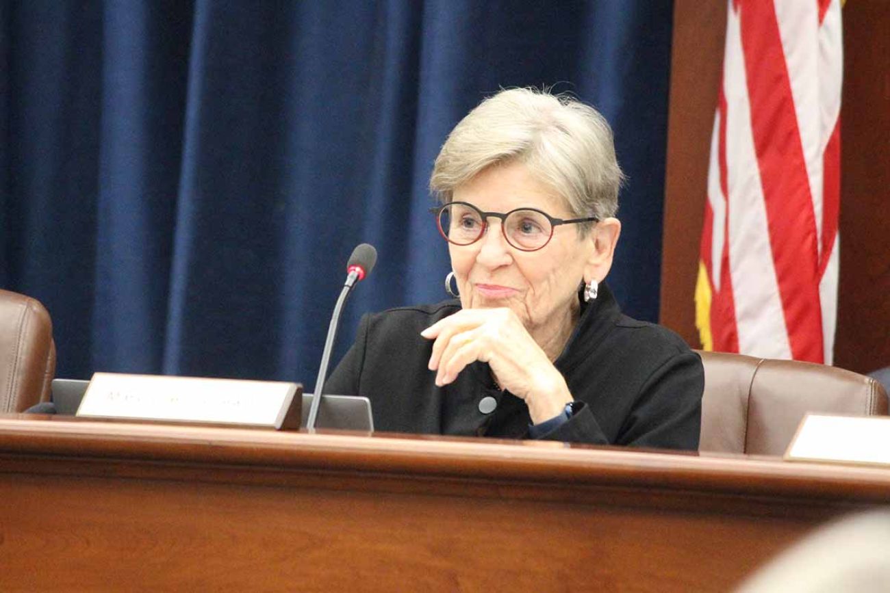 Mary Ellen Gurewitz sitting at a brown table. She is wearing black