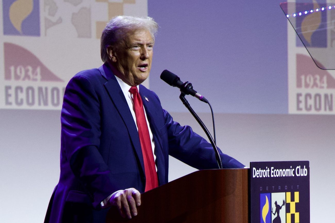 Donald Trump speaking into a microphone on stage.