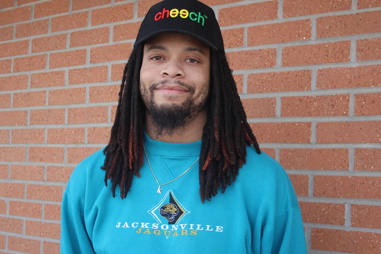 Daniel Carr poses for a picture in front of a brick wall. 