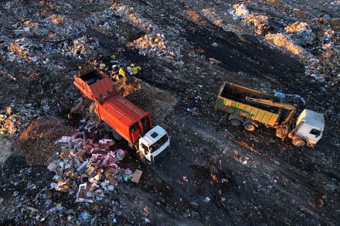 Garbage truck unloads rubbish in landfill.