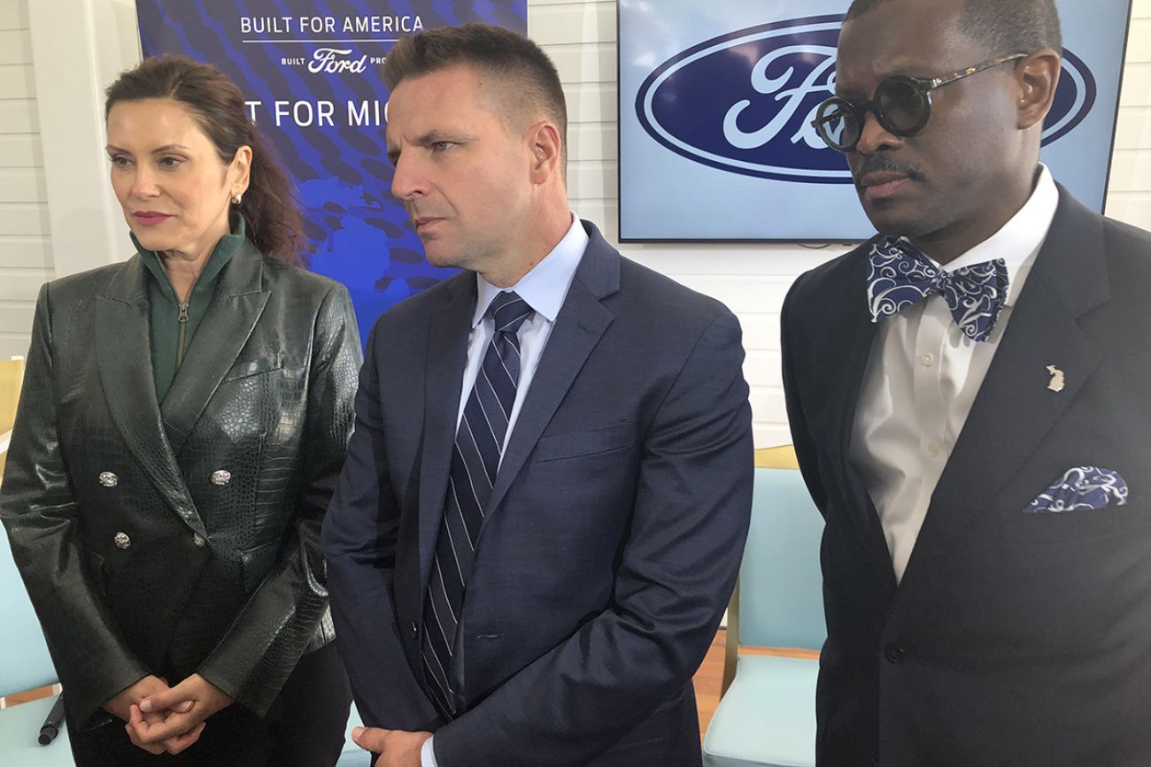 three people standing at a press conference