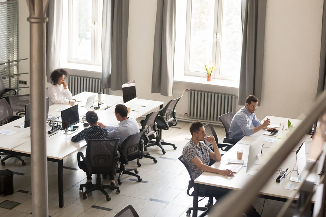 Top view of diverse people working together on computer performing daily routine tasks in coworking space, multiracial millennial men and women busy using devices discussing projects in shared office