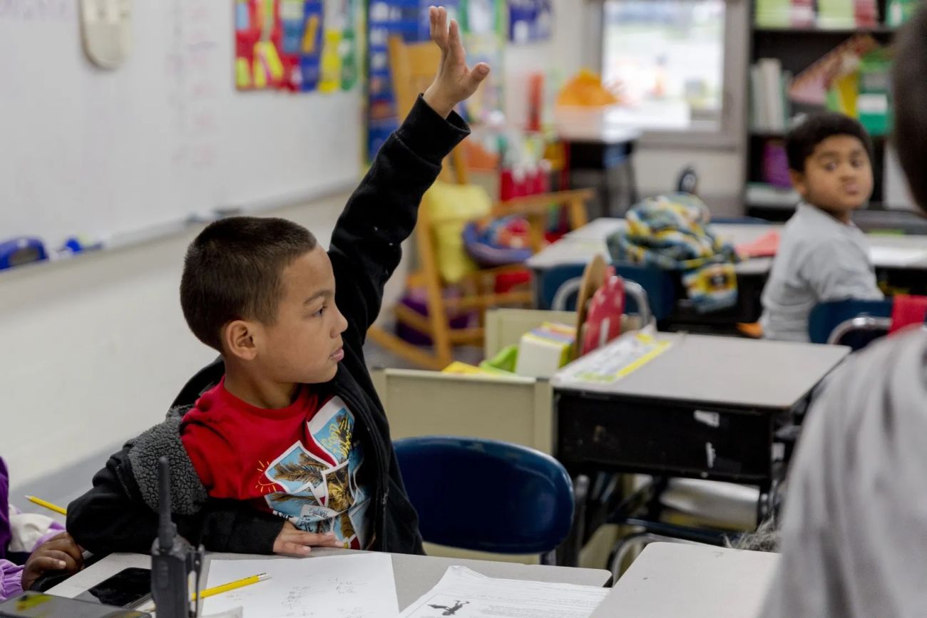 child raising hand in classroom