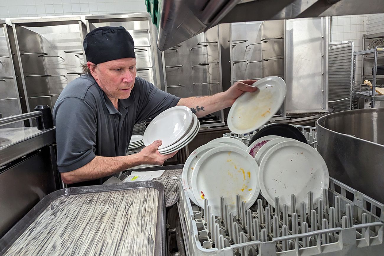 man putting dishes in dishwasher