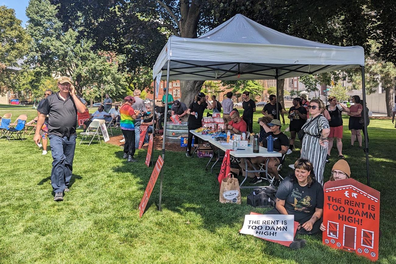 people holding signs about rent being too high outside