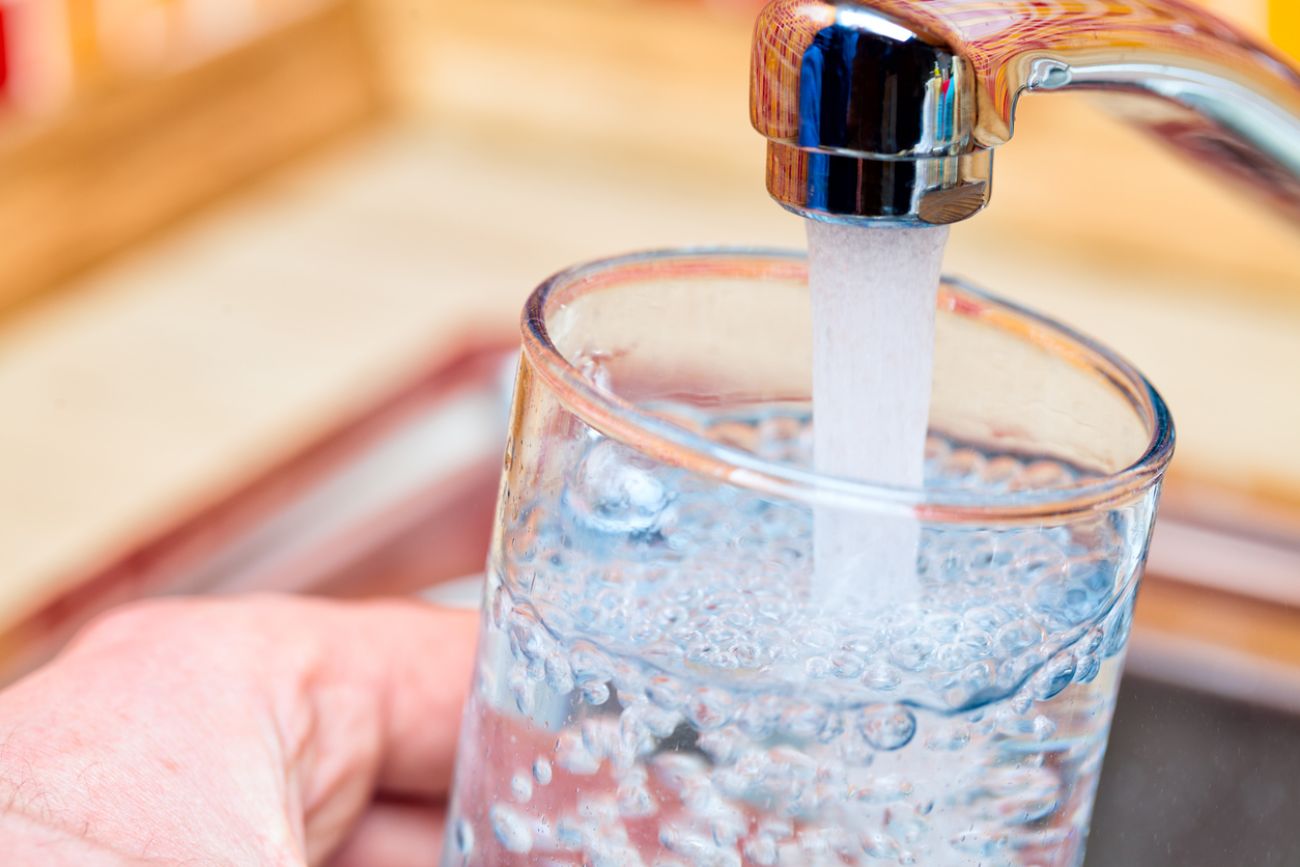  Point of view shot of a man pouring a glass of fresh water from a kitchen faucet