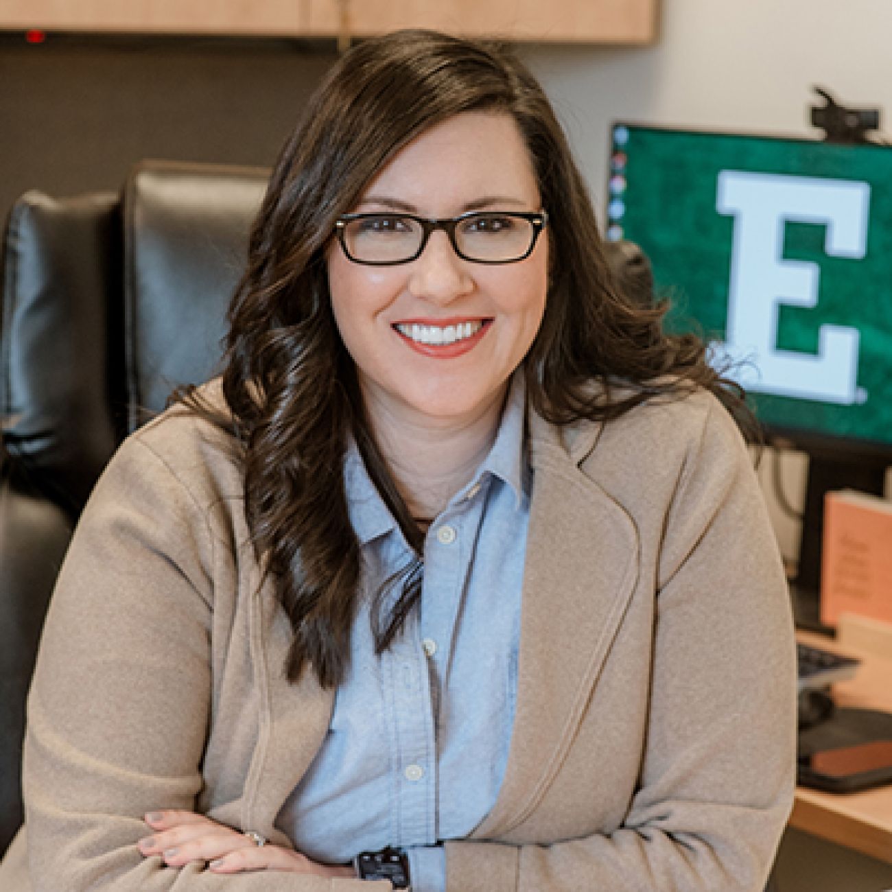 Katie Condon, wearing a brown jacket and a blue shirt.