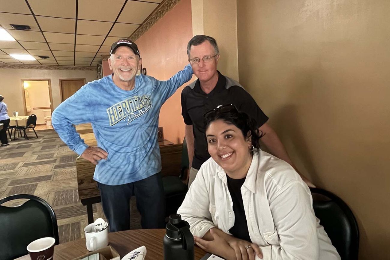 Three people pose for a picture inside a bakery 