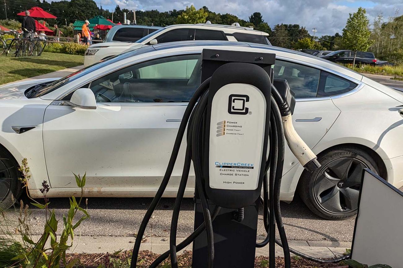 An EV plug next to a white car