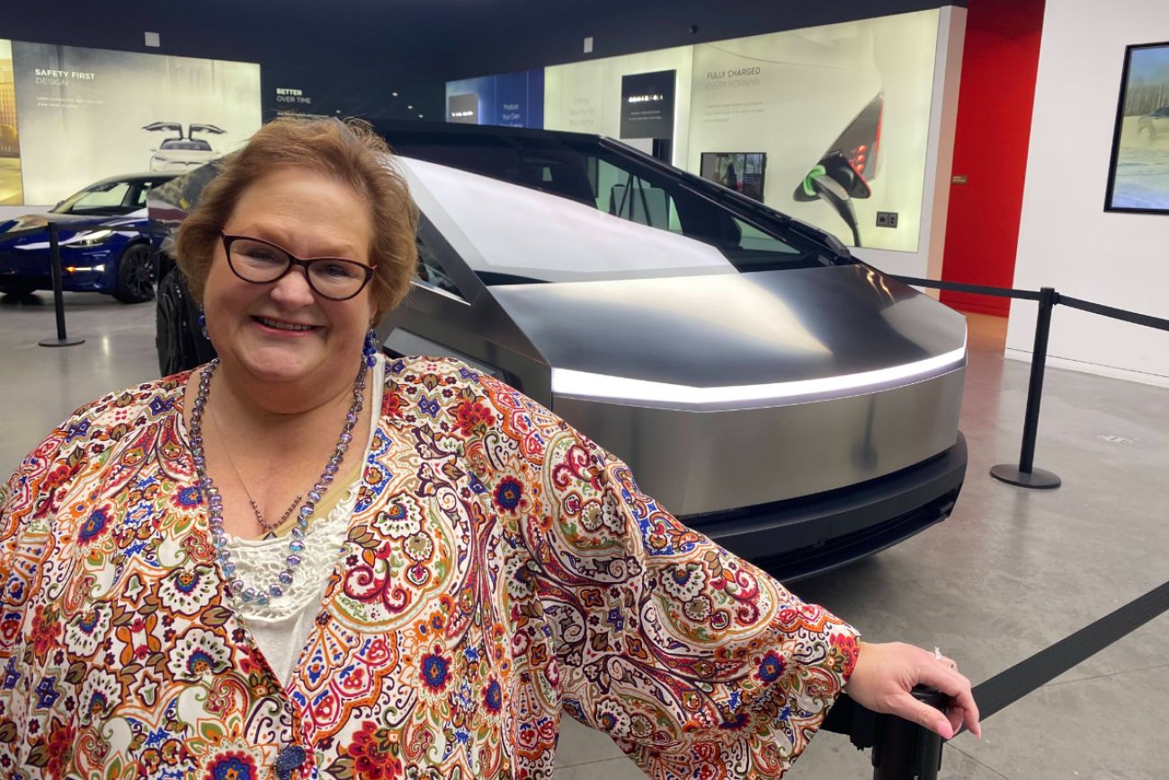  Kelli Sloan standing in front of an electric car