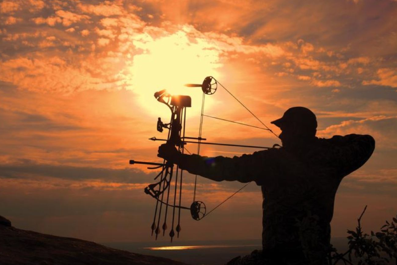 Silhouette of a male hunter shooting a bow and arrow