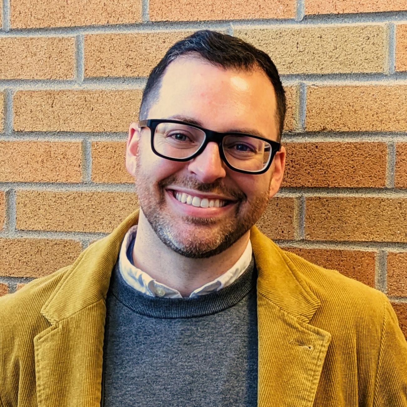 Jonathan Stoltman poses for a picture in front of a brick wall