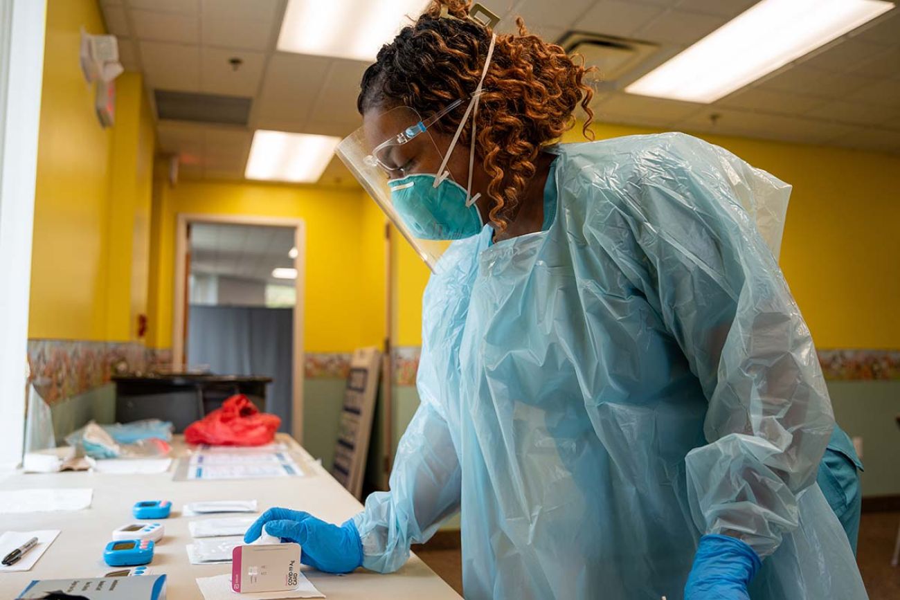 Beth Schuckman wears blue PPE gear while processes aCOVID test