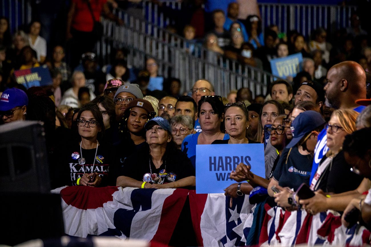 A woman holding an Harris Walz sign at a rally