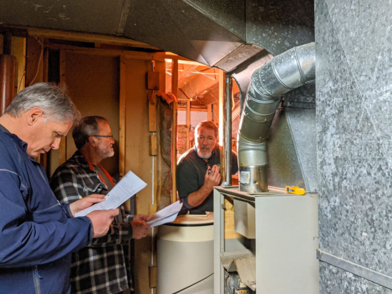 Three men look at a furnace 