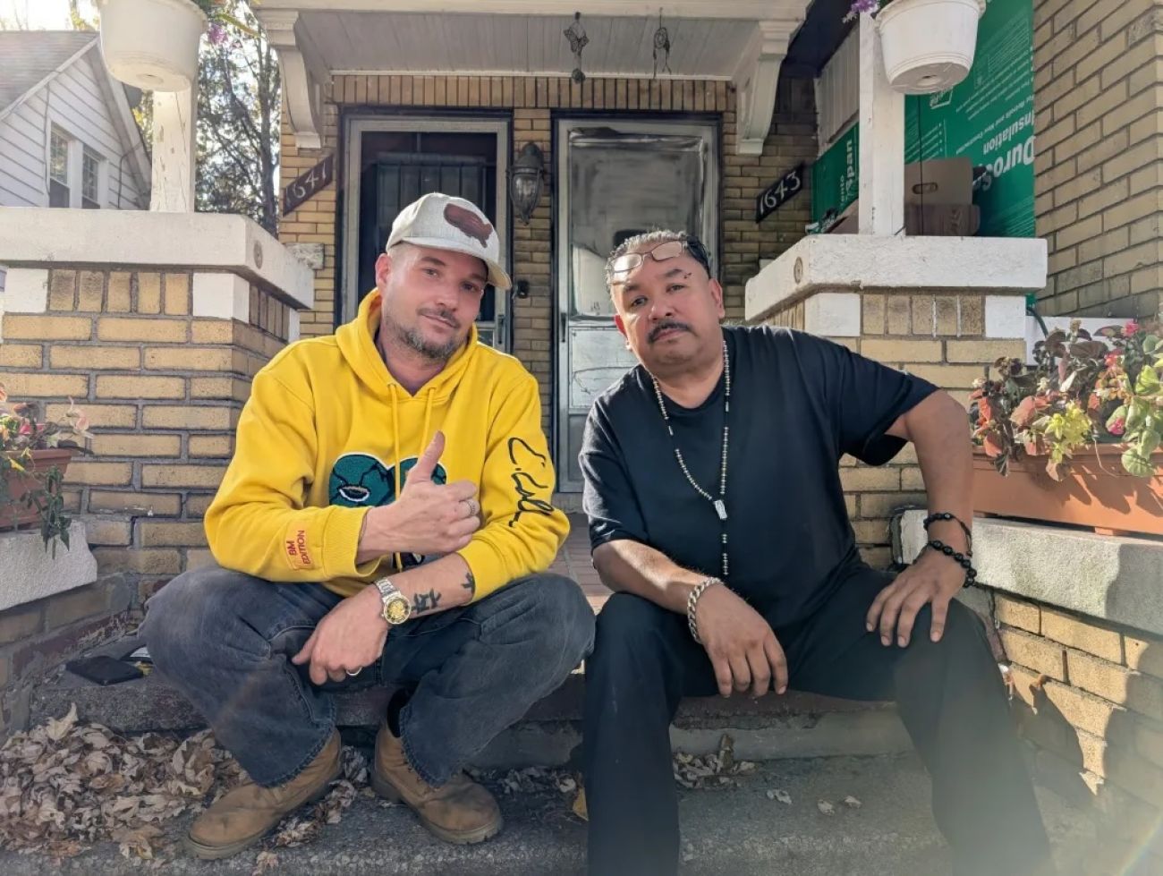 David Noyce and Ernesto Alonzo sitting in front of a house