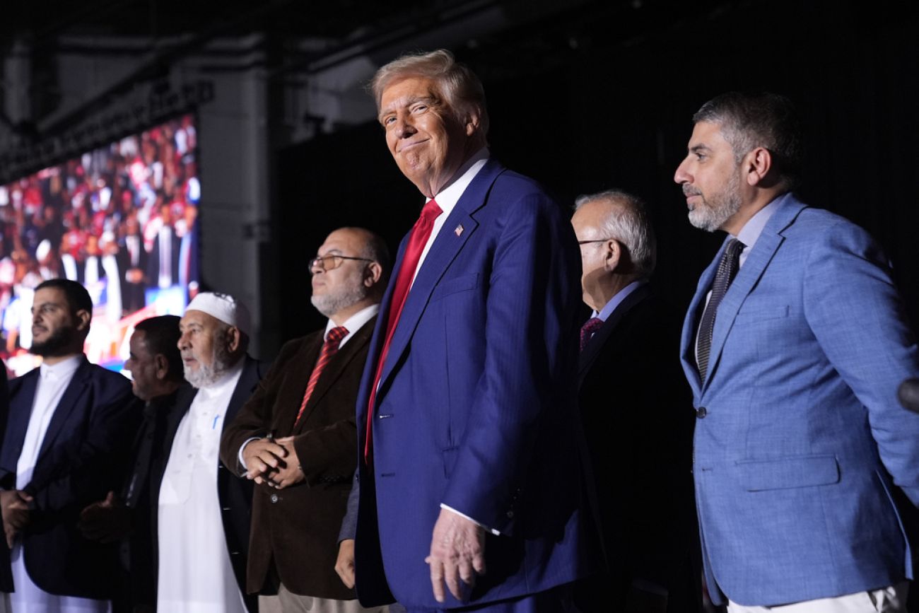 Donald Trump, wearing a blue suit, stands alongside Muslim leaders