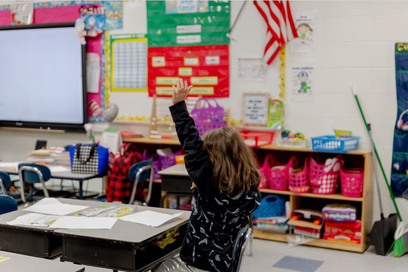 A child raising their hand in a classroom