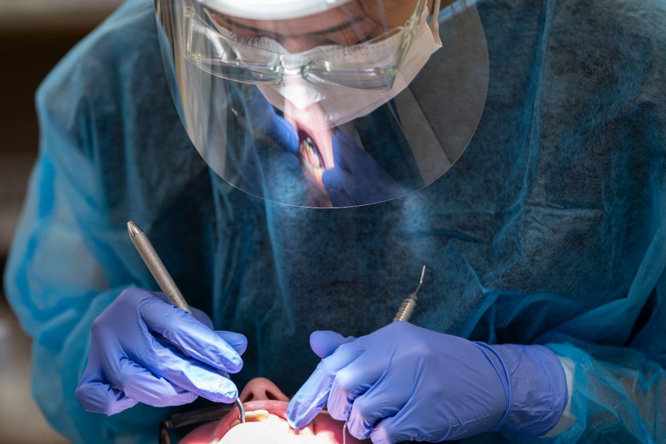 Dental hygienist student cleans a patient's teeth