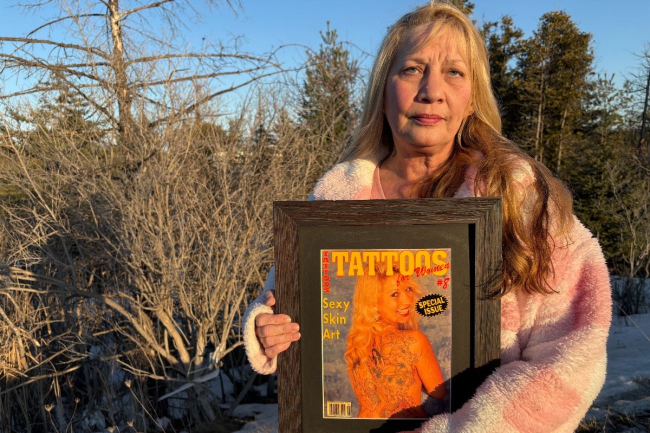 Woman stands holding framed magazine cover featuring herself