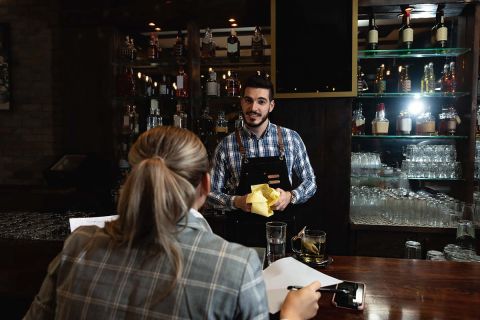 Smiling bartender talking to a customer at counter.