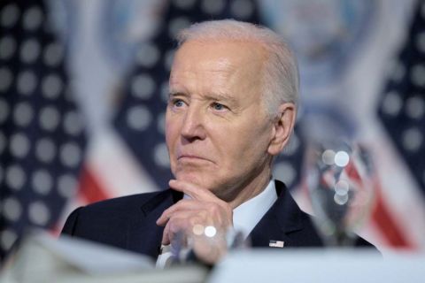 Joe Biden sitting down, American flags behind him