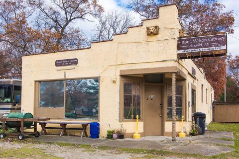 Historic Wilson Grocery in Idlewild, Michigan. It's a small tan building. There's a brown sign with the store's anem