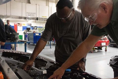 Two people looking inside the hood of the car