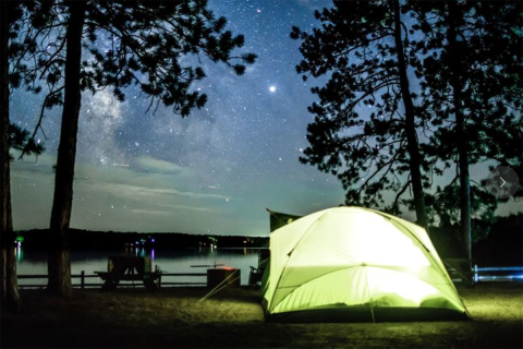 A green tent in the woods at night