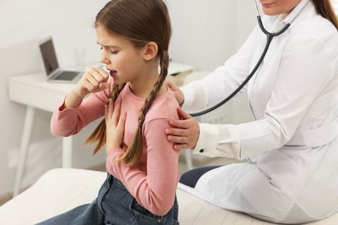 Doctor examining coughing girl in hospital