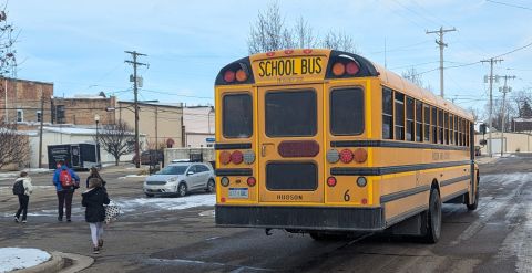 Kids walking away from the school bus. There's snow on the ground