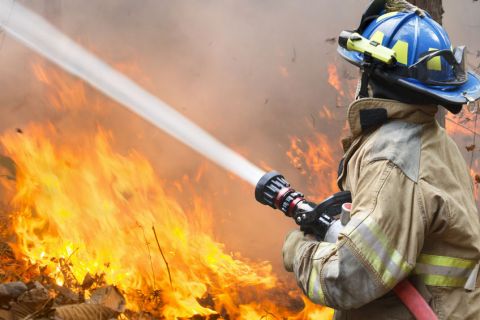 A firefighter putting out a fire with a water hose