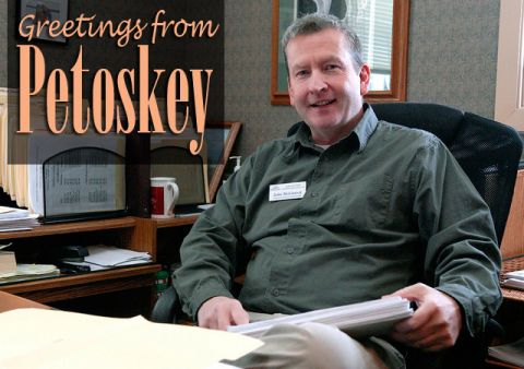 A postcard that says "Greetings From Petoskey" above a picture of John McLintock