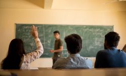 Group of student sitting at their desks and one student raised her hands to ask doubt to teacher.