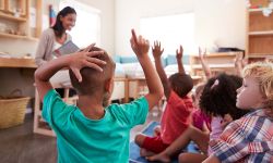 students in a classroom raising hands