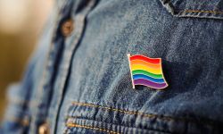 Close up of LGBT pin in the form of a flag is pinned on blue jeans jacket.