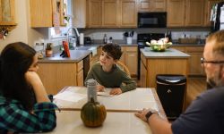 child on dining room table while parents looking at her