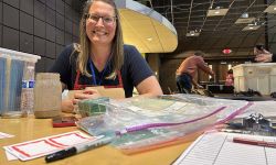 Danielle Bellgowan sitting at a table. The table has name tags and a sign up sheet 