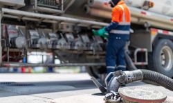 A tanker truck driver delivers gasoline to a gas station