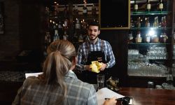 Smiling bartender talking to a customer at counter.