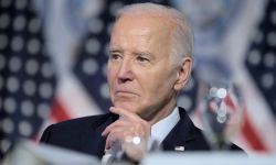 Joe Biden sitting down, American flags behind him