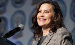 Michigan Gov. Gretchen Whitmer, wearing a grey jacket, speaks into a microphone