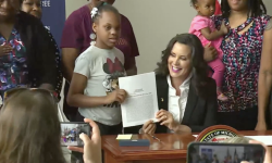 Michigan Gov. Gretchen Whitmer holding up a paper next to a child