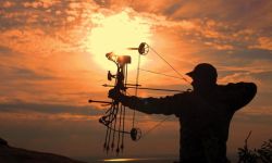 Silhouette of a male hunter shooting a bow and arrow