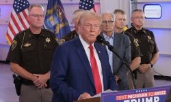 Donald Trump speaking in a microphone, officers are standing behind him