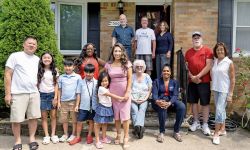 Rep. Mai Xiong poses with her family in front of a house