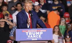 Donald Trump on stage; supporters are cheering behind him