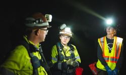 Three miners wearing hard hats with lights on it 