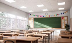 The classroom have white walls and wooden floor, decorated with wooden tables and chairs, large windows overlooking natural views.