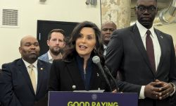 Whitmer stands a podium with people around her